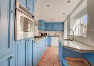 una cocina con armarios azules y fregadero en Sandcastle Cottage, en Southwold
