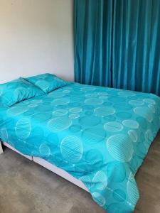 ein Bett mit blauer Decke in einem Schlafzimmer in der Unterkunft Agréable maison familiale in Carcans