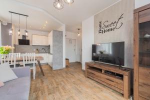 a living room with a large television and a kitchen at Flatbook Apartamenty - Sztutowo Baltic Twins in Sztutowo