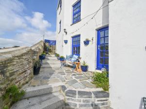 a stone stairway leading to a white building with blue doors at Holiday Home Dolphin Cottage by Interhome in Mevagissey