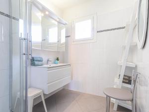 a white bathroom with a sink and a chair at Apartment La plage du Cap by Interhome in Roquebrune-Cap-Martin