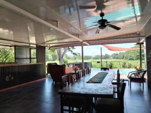 a patio with a table and chairs and a ceiling fan at Natalias Beach House in Matapalo