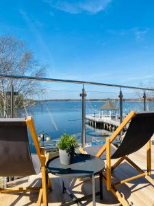 een balkon met 2 stoelen en een tafel en uitzicht op het water bij Apartament MoLoo II in Ostróda