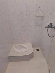 y baño blanco con ducha y aseo. en Guguak Puro Guest House en Padangpanjang