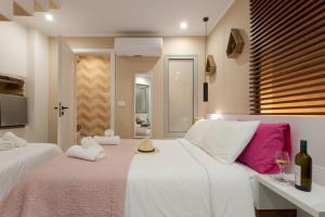 1 dormitorio con 2 camas y almohadas blancas y rosas en Mitos mini suites en La Canea