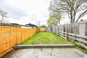 an orange fence with a grass field next to it at Stunning 2 Bed House with Parking in Dagenham in Goodmayes