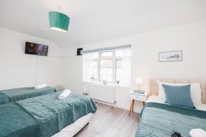sypialnia z 2 łóżkami i oknem w obiekcie Stunning 2 Bed House with Parking in Dagenham w mieście Goodmayes
