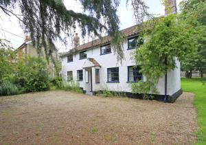 a white house with a large yard in front of it at Sherfield Cottage in Snape