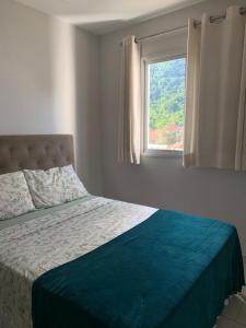 a bedroom with a bed and a window at Ap aconchegante 12 min a pé p Praia in Praia Grande