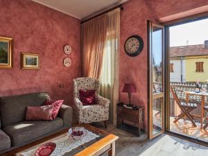 een woonkamer met een bank en een stoel en een balkon bij Apartment Il Castello by Interhome in Casciago