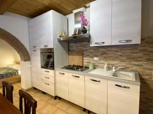una cocina con armarios blancos y fregadero en Apartment Angolino di Borgo by Interhome, en Montescudaio