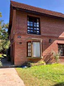 a brick house with two windows and a driveway at Duplex en Alquiler Pinamar in Pinamar