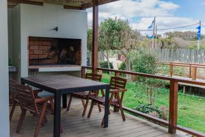 a wooden table and chairs on a deck with a fireplace at Las Eduardas in La Paloma