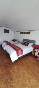 a group of beds in a room with white walls at Uros Amaru Marka Lodge in Uros