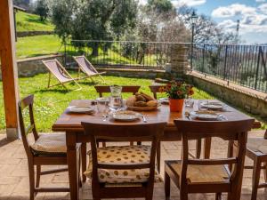 een houten tafel met stoelen en eten op een patio bij Holiday Home Civitella by Interhome in Scansano