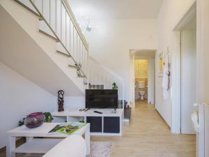 a white living room with a tv and a staircase at Holiday Home Rita by Interhome in Torre del Lago Puccini