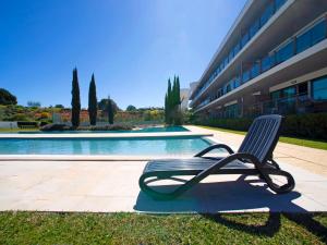 a chair sitting in the grass next to a swimming pool at Apartment Sunna Residence by Interhome in Vilamoura