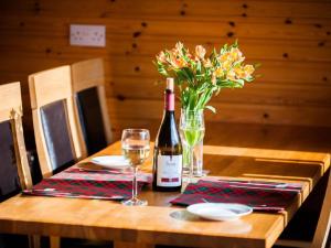 una botella de vino y un jarrón de flores sobre una mesa en Holiday Home Achmony Number 7 by Interhome, en Drumnadrochit
