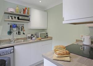 a kitchen with white cabinets and bread on a counter at Stones Throw in Southwold