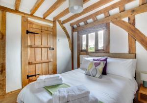 a bedroom with a white bed with a wooden ceiling at Stone Cottage in Darsham