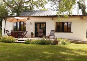 Haughley的住宿－Straw Bale Cottage，院子里的房屋,配有椅子和遮阳伞