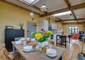 cocina y comedor con mesa de madera con flores en Straw Bale Cottage en Haughley