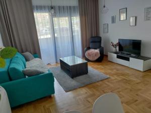 a living room with a blue couch and a tv at Harmony Suite in Trebinje