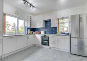 a kitchen with white cabinets and blue tiles at Stonehurst in Aldringham