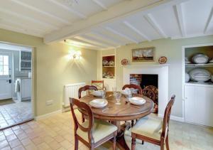 een eetkamer met een tafel en stoelen en een open haard bij Boot Cottage in Sudbourne