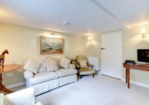 een woonkamer met een witte bank en een tafel bij Boot Cottage in Sudbourne
