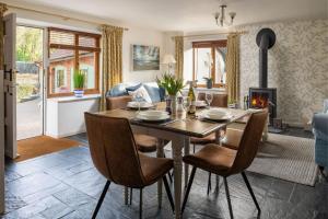 comedor con mesa, sillas y chimenea en Cuckoo Cottage - Luxury Cottages, en Ilfracombe