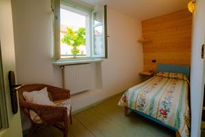 1 dormitorio con cama, ventana y silla en Agriturismo Maso Giomo en Brentonico
