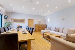 uma sala de estar com uma mesa e um sofá em The Roost Group - 29 Guests - Two Luxury Barns em Gravesend