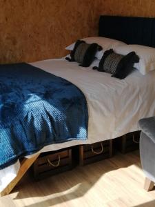 a bed with a blue blanket and pillows on it at Lakes and Eden Valley. Thornhill Cabin in Long Marton