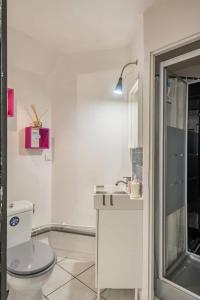 La salle de bains blanche est pourvue de toilettes et d'un lavabo. dans l'établissement Studio indépendant et chambres dans maison avec jardin-Carre de Soie, à Vaulx-en-Velin