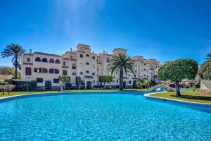 a large pool in front of a large building at La Isla Casa Barnaby in Platja de l'Arenal