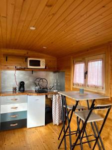 a kitchen with a table and a microwave in a cabin at La p'tite Bohème in Gouttières