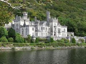 a large castle sitting on the side of a lake at Clonbur House - Two bedroom village apartment in Galway