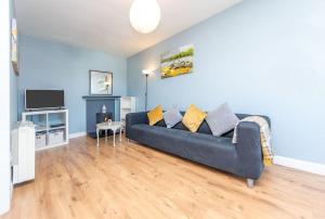a living room with a blue couch and a tv at Clonbur House - Two bedroom village apartment in Galway