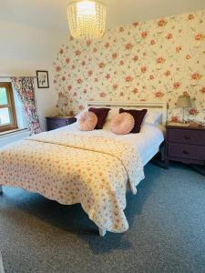- une chambre avec un grand lit et du papier peint floral dans l'établissement Luxury Village Cottage 5 mins to Alton Towers, à Alton