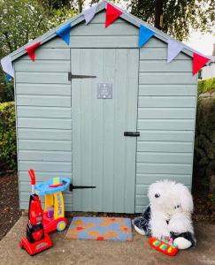 a white dog sitting in front of a toy shed at Luxury Village Cottage 5 mins to Alton Towers in Alton
