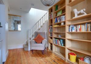 a staircase with book shelves and a chair with an orange pillow at Suffolk Cottage in Southwold