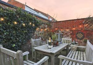 a wooden table and chairs on a patio with a brick wall at Suffolk Cottage in Southwold
