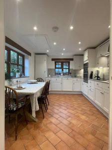 a kitchen with a table and chairs and a kitchen with white cabinets at Luxury Village Cottage 5 mins to Alton Towers in Alton