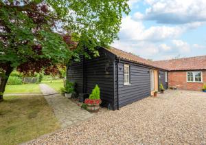 a black shed next to a house at Sundial Lodge in Wilby