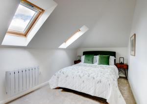 a white bedroom with a bed and a window at Swallows Roost in Sudbury