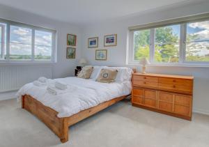 a bedroom with a bed and a dresser and windows at Sunset Cottage in Barking