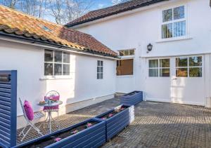 a white house with a patio and a table and chairs at The Coach House at Hill House in Eye