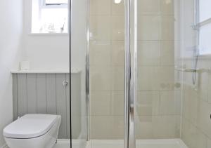 uma casa de banho branca com um chuveiro e um WC. em The Cornerstone em Southwold