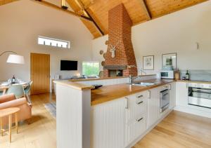 a kitchen with white cabinets and a brick wall at The Folly Barn in Debenham